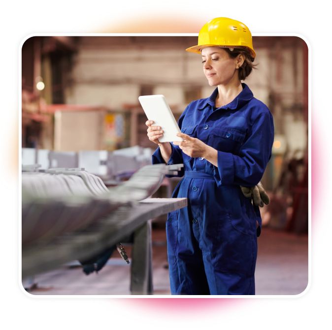 Woman looking at a tablet in a jumpsuit and hard helmet.