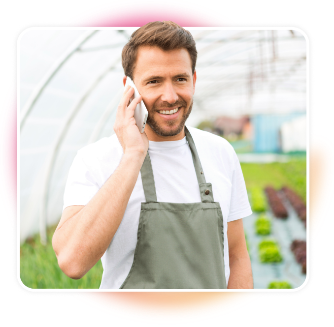 Greenhouse male employee smiling talking on the phone.