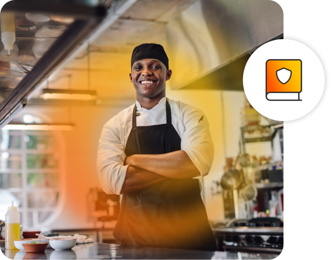 Man smiling with his arms crossed, wearing a chef uniform in a kitchen. Icon for safe operating procedures.