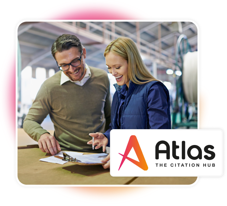 Man and woman talking in warehouse about information on a clipboard. Altas logo.