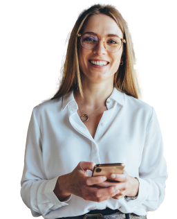 Woman in business causal smiling at camera, while holding a cell phone.