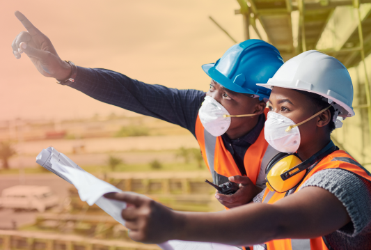 Two employees are wearing PPE and identifying hazards in construction